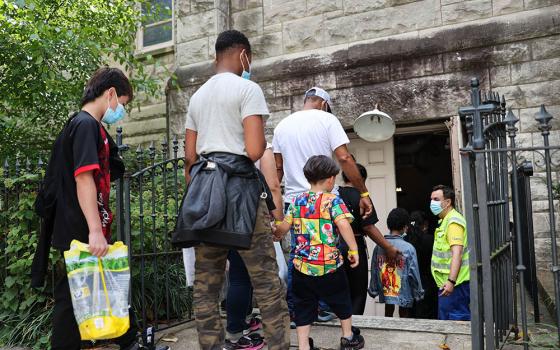 Migrants who arrived on a bus from Arizona step into the parish hall at St. Peter's Church on Capitol Hill in Washington Aug. 5, 2022. The local church, partnering with SAMU First Response, began offering hospitality in late July to migrants arriving on buses sent to Washington by the governors of Texas and Arizona. (CNS/Catholic Standard/Andrew Biraj)