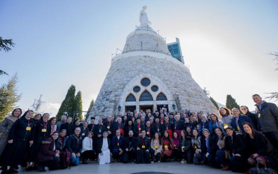 A large group, including women religious, takes a picture outside a chapel