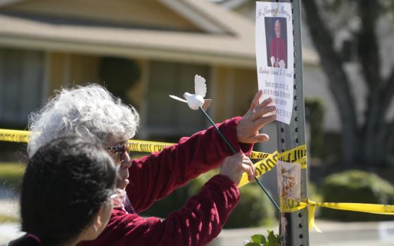 Rosa Maria Perez, with her granddaughter Abigail Gil, pay their respects to Bishop David O'Connell at the corner of his home in Hacienda Heights, California, Feb. 19. According to the Los Angeles County Sheriff's Department, detectives are investigating the death of O'Connell, who was shot and killed Saturday just blocks from a church, as a homicide. (AP/Damian Dovarganes)