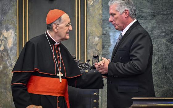 A white cardinal shakes hands with a white man in a suit