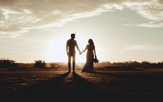 Silhouette of a groom and a bride holding hands (Unsplash/Jonathan Borba)