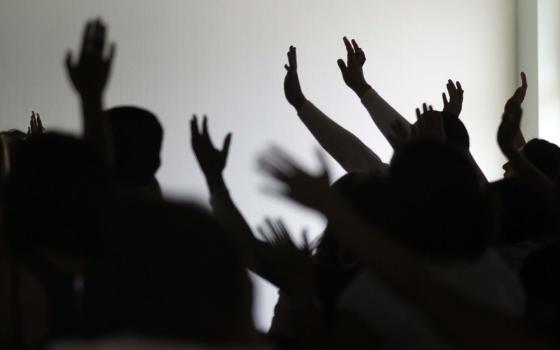 The silhouettes of people with their hands raised in the air