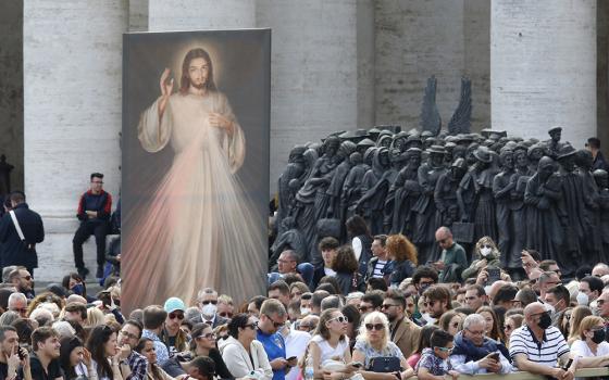An image of Jesus of Divine Mercy and the "Angels Unawares" sculpture are seen in St. Peter's Square as people wait for Pope Francis to lead the "Regina Coeli" April 24, 2022, at the Vatican. (CNS/Paul Haring)