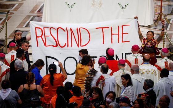 Indigenous people hold a banner calling on Pope Francis to "rescind the doctrine," an apparent reference to the so-called Doctrine of Discovery, a collection of old papal teachings that encouraged explorers to colonize and claim the lands of any people who were not Christian, placing both the land and the people under the sovereignty of European Christian rulers. The incident occurred during a papal Mass at the National Shrine of Sainte-Anne-de-Beaupré in Quebec July 28, 2022. (CNS photo/Guglielmo Mangiapan