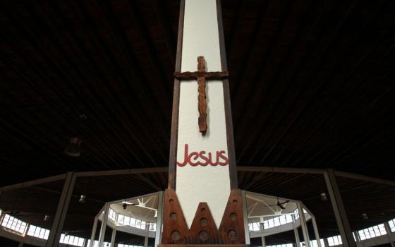 A cross with the word Jesus under it stands on a white pole