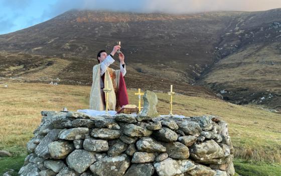 Fr. Gerard Quirke raises the chalice at Mass Rock overlooking Keem Bay on Ireland's Achill Island April 4, 2021. The church in Ireland is launching a Year for Vocations as it grapples with a steep decline in seminary numbers and with aging priests. (OSV News/Courtesy Irish Catholic/Seán Molloy)