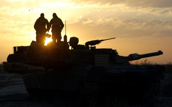 Soldiers standing on tanks are silhouetted against  Tank crew members of the U.S. Marines 3rd Battalion, 4th Regiment, are silhouetted at sunrise near Baghdad, Iraq.