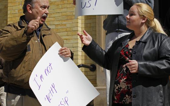 Man speaks at protest while daughter signs for him. 