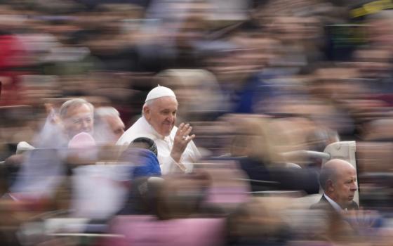 A photo where everything is blurry but Pope Francis. Francis is surrounded by a blurry crowd.