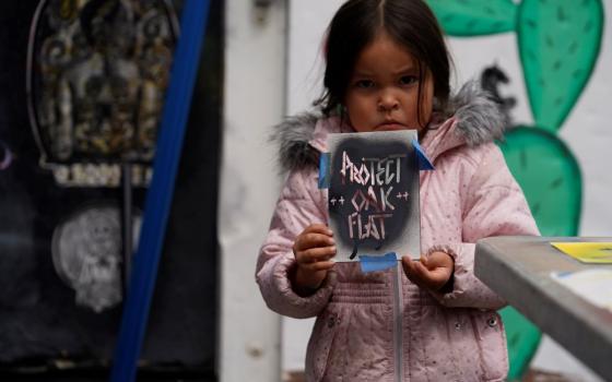 Apache Stronghold member Raetana Manny, 4, shows a sign to save Oak Flat