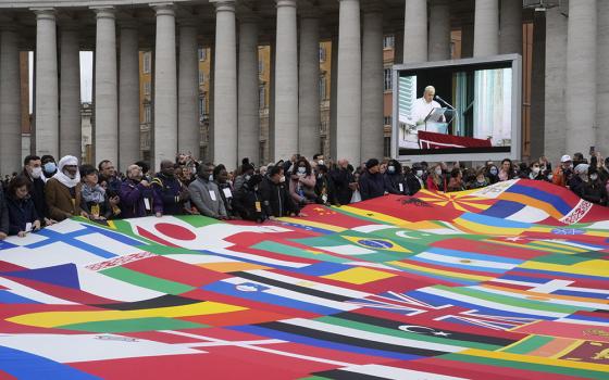 Members of a migrants association hold a huge banner made with the world's flags as Pope Francis delivers the Angelus prayer in St. Peter's Square at the Vatican Nov. 28, 2021. (AP/Gregorio Borgia)