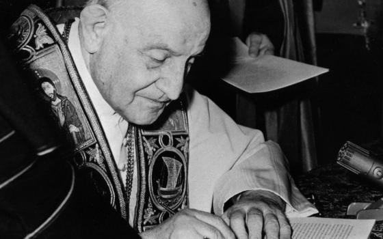 Black and white photo of a pope signing a document