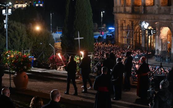 People, including refugees, representing different parts of the world carry the cross in procession as they near the end of the Good Friday Way of the Cross service at Rome's Colosseum April 7, 2023. Pope Francis did not attend the event because of the cold, the Vatican said. (CNS photo/Chris Warde-Jones)