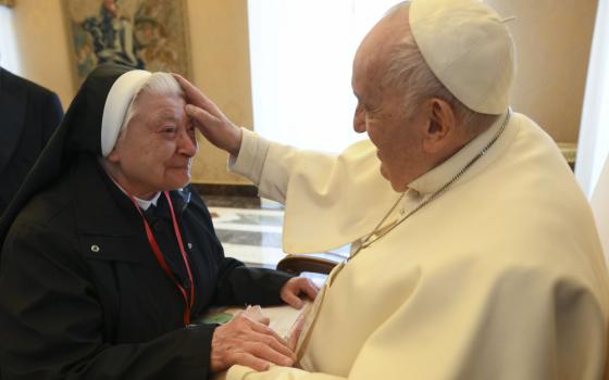 Pope Francis places his hand on a woman religious' forehead. 
