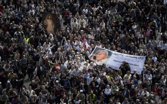 Pilgrims holding an image of Divine Mercy and others holding a banner featuring St. John Paul II, who instituted the universal celebration of Divine Mercy Sunday, join Pope Francis for the recitation of the "Regina Coeli" prayer April 16, 2023, in St. Peter's Square at the Vatican. (CNS photo/Vatican Media)