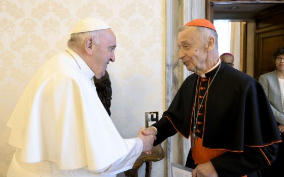 Pope Francis shakes an older white cardinal's hand