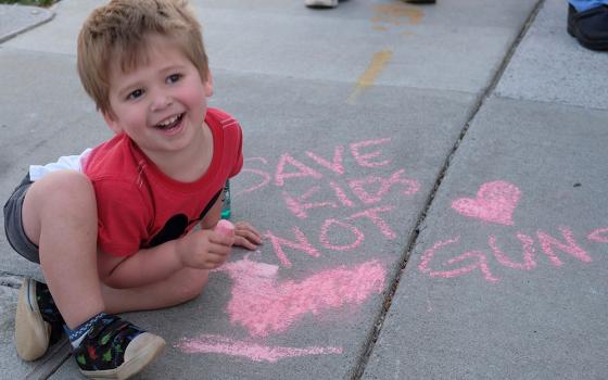 A 3-year-old boy plays with chalk as people gather for an event outside the Tennessee Capitol in Nashville April 18 to push the Legislature to address gun violence. (OSV News/Tennessee Registe/Katie Peterson)