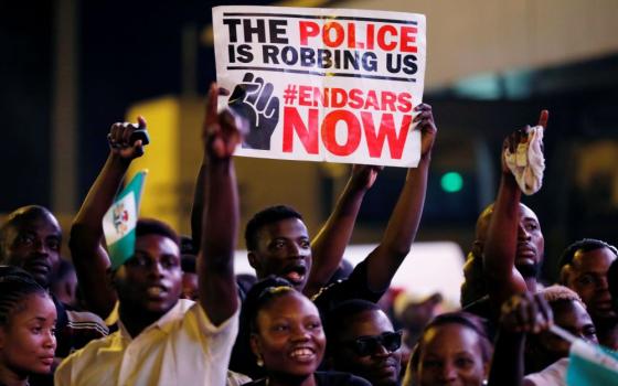 A demonstrator holds a sign during protest in Lagos, Nigeria, Oct. 17, 2020, over alleged police brutality by SARS, or Special Anti-Robbery Squad. The police unit, created in 1992, had long been accused of harassing and physically abusing civilians. It was disbanded in October 2020. (CNS photo/Reuters/Temilade Adelaja)