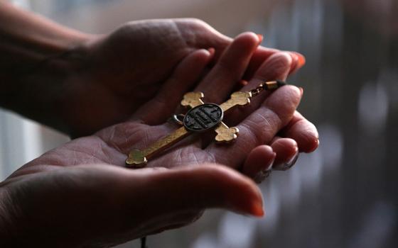 Christine Zuba holds the cross she wears when serving as a eucharistic minister at Sts. Peter and Paul Catholic Church at her home Feb. 14, 2022, in Blackwood, New Jersey. After coming out as transgender at age 58, Zuba, a lifelong Catholic, was welcomed into the parish. U.S. Catholic bishops issued a document dated March 20 rejecting gender-affirming medical treatments for transgender individuals and reasserting that such procedures must not be performed by Catholic providers. (AP photo/Jessie Wardarski)