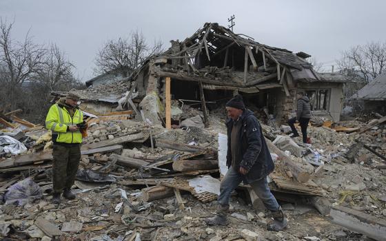 Villagers walk in the debris of private houses ruined in Russia's night rocket attack in a village, in Zolochevsky district in the Lviv region, Ukraine, March 9. NCR board member David Bonior and contributor Fr. Peter Daly traveled to Ukraine and Poland in March. (AP photo/Mykola Tys)