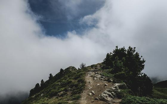A hilltop with an opening in the clouds above it (Unsplash/Paul Pastourmatzis)