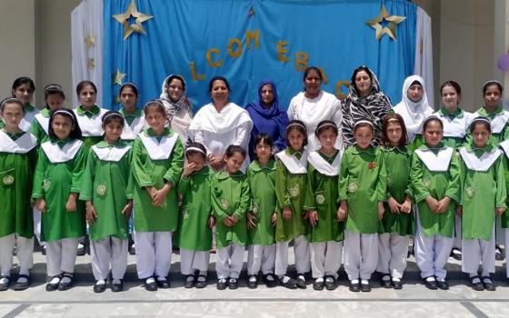 Presentation Sisters are pictured May 24 with students who survived a gun attack May 16 at Sangota Public School in Swat Valley, Pakistan. Classes resumed May 24 when the students recited prayer in the morning assembly. A sign behind them reads "Welcome back." (Courtesy of Sr. Teresa Younas)