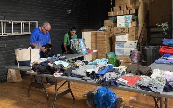 Fr. Gustavo Meneses sorts and folds clothes for migrants May 13 at a temporary shelter the Diocese of El Paso set up to care for migrants at Our Lady of Assumption Parish in El Paso, Texas. The diocese has been working with local governments and organizations to prepare for an influx of migrants in the border city. (NCR photo/Rhina Guidos)