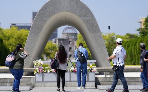 Visitors pray before flowers placed at the Hiroshima Peace Memorial Park in Hiroshima, Japan, on May 17, ahead of the G-7 summit in the city. (AP/Hiro Komae)