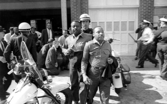 Martin Luther King and another Black man stand in front of a white police officer with a scooter
