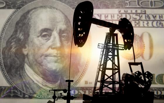 Silhouette of an oil drill against a $100 bill (Dreamstime/Mrsash174)