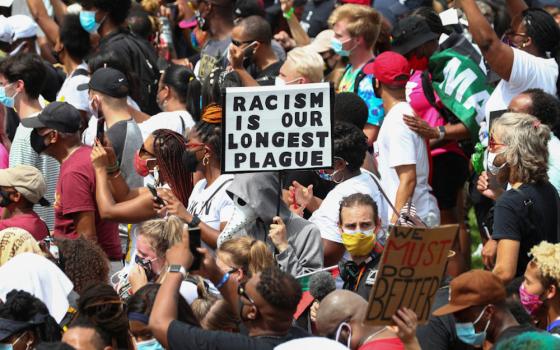 Protesters stand with a sign reading "Racism Is Our Longest Plague" in Washington Aug. 28, 2020, during the "Get Your Knee Off Our Necks" Commitment March on Washington 2020 in support of racial justice. (CNS/Reuters/Tom Brenner)