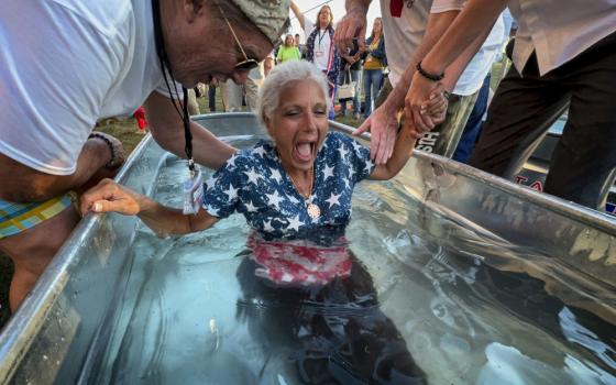 A woman is baptized during the ReAwaken America Tour at Cornerstone Church in Batavia, New York, on Aug. 12, 2022. In the version of America laid out at the ReAwaken tour, Christianity is at the center of American life and institutions, it's under attack, and attendees need to fight to restore and protect the nation's Christian roots. (AP/Carolyn Kaster)