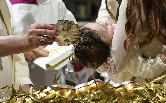 Pope Francis baptizes one of 13 babies during a Mass celebrating the feast of the Baptism of the Lord in the Sistine Chapel Jan. 8 at the Vatican. (CNS/Vatican Media)