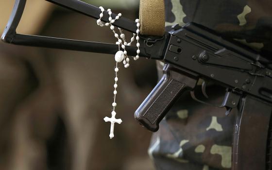A rosary is pictured hanging from a machine gun in an undated file photo as Ukrainian soldiers stand at their positions near the Ukrainian town of Pervomaysk. (OSV News/Reuters/Gleb Garanich)