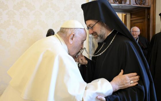 Pope Francis kisses an Orthodox leaders necklace while embracing the leader's arm