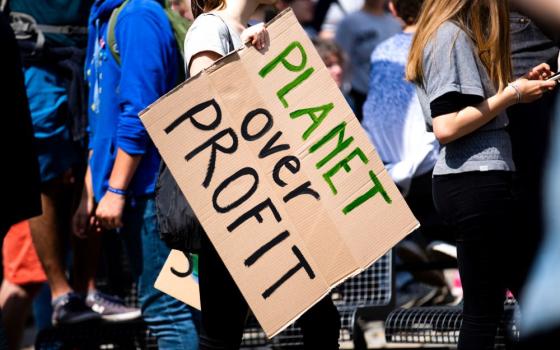 Person at a rally holds a sign that reads: "planet over profit"