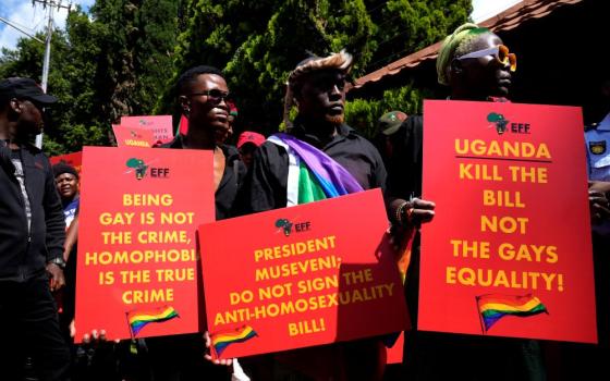 People hold signs supporting lgbtq rights in Uganda.