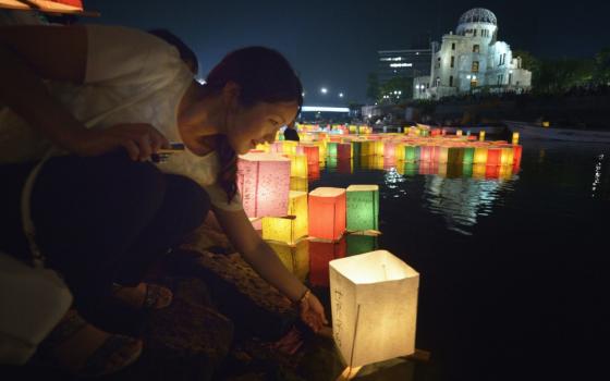 A woman sets a floating candle lantern on the river Aug. 6, 2015, in Hiroshima, Japan. "Peace is founded on the primary relationship that exists between every human being and God himself, a relationship marked by righteousness," declares the Compendium of the Social Doctrine of the Church. (CNS photo/Paul Jeffrey)