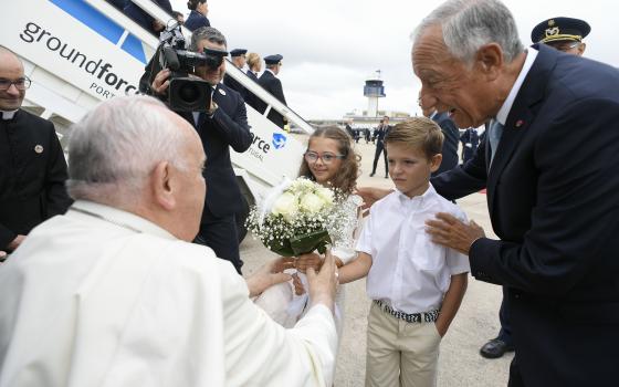 Portuguese President Marcelo Rebelo de Sousa and children carrying flowers greet Pope Francis upon his arrival at Figo Maduro Air Base in Lisbon Aug. 2, 2023. The pope began a five-day trip to Portugal to participate in World Youth Day. (CNS photo/Vatican Media)