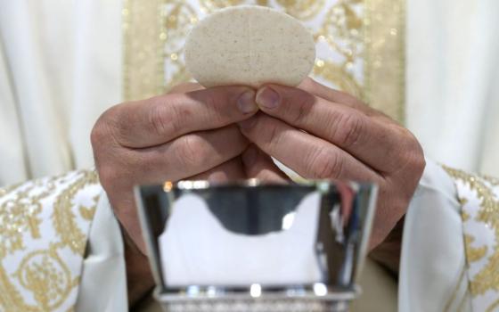 A priest holds the Eucharist.