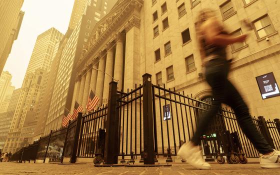 A pedestrian walks past the haze-shrouded New York Stock Exchange building in New York City June 7. Smoke from intense Canadian wildfires severely affected air quality in the Northeastern United States in early June. (AP/J. David Ake)