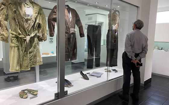 A bishop at the Centro Romero in San Salvador on Jan. 18, 2022, looks at a display of clothes the Jesuits and their housekeepers were wearing when they were murdered in 1989. (NCR photo/Rhina Guidos)