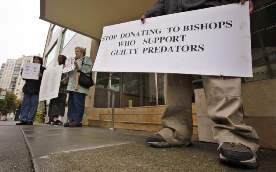 A person holds a sign that reads, "stop donating to bishops who support guilty predators."