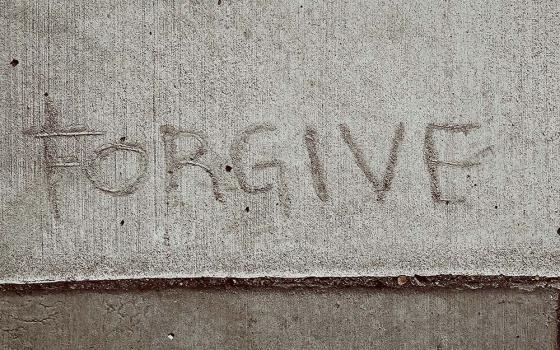 The word "FORGIVE" drawn into concrete (Unsplash/Christopher Stites)