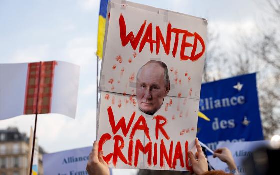 A person near the Place de la Republique in Paris holds a placard with an image of Russian President Vladimir Putin during an anti-war protest March 5, 2022, following Russia's invasion of Ukraine. (OSV News/Reuters/Johanna Geron)