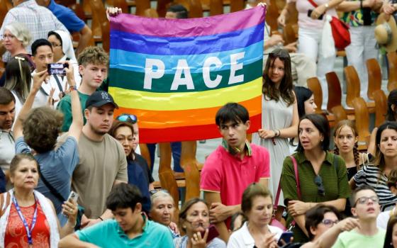 Young people hold a flag reading "peace" in Italian at the end of Pope Francis’s weekly general audience in the Paul VI Audience Hall at the Vatican Aug. 23, 2023. (CNS photo/Lola Gomez)