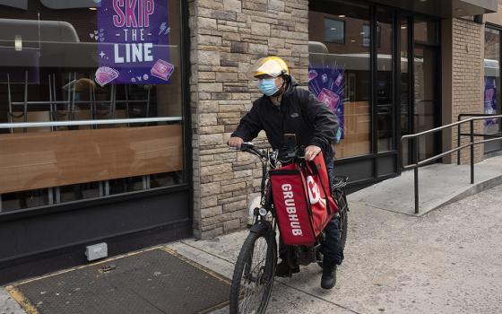 A delivery man bikes with a food bag from Grubhub on April 21, 2021, in New York. Uber Eats, DoorDash and Grubhub sued New York City on July 6, 2023, to block its new minimum pay rules for food delivery workers. (AP/Mark Lennihan, File)