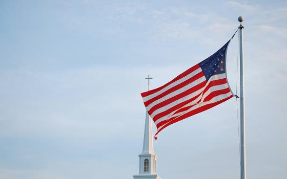 An American flag flies in front of the steeple of a unnamed church (Unsplash/Brad Dodson)