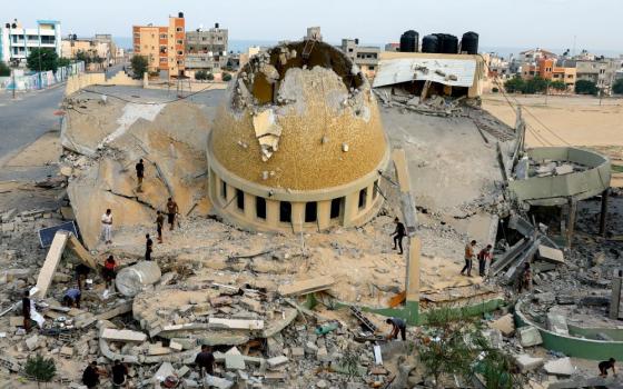 People look at the rubble of a mosque. 