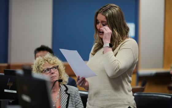 Jenna Ellis stands in courtroom while holding a piece of paper and wiping her eye. 
